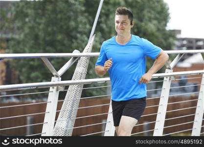 Young Man Running In Urban Setting Listening To Music