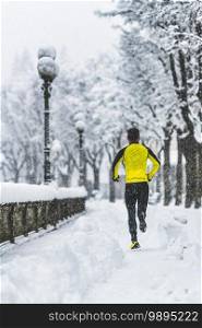 Young man runs on snowy sidewalk in winter