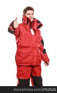Young man sailor wearing red waterproof wind jacket showing thumb up success hand sign gesture isolated on white. Sailing yachting cruise. Studio shot.