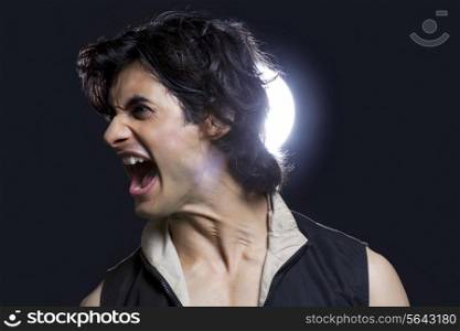 Young man screaming in front of spotlight
