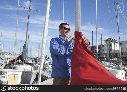 Young man securing sail of boat