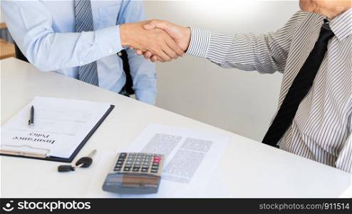 young man shaking hands with an insurance agent or investment adviser realtor after signing contract document accept agreement making purchase deal investment or greeting at meeting