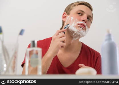 Young man shaving at home