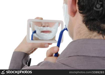 Young man shaving at the mirror. Isolated on white background