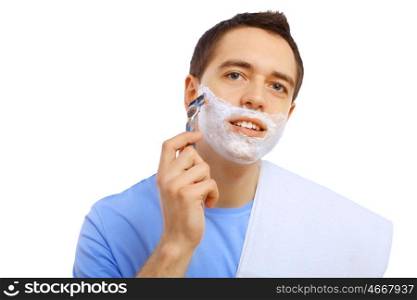 Young man shaving. Young man in blue T-shirt shaving himself
