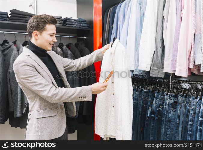 young man shop checking price tag shirt