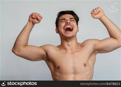 young man shouting. a young man shouting and flexing muscles