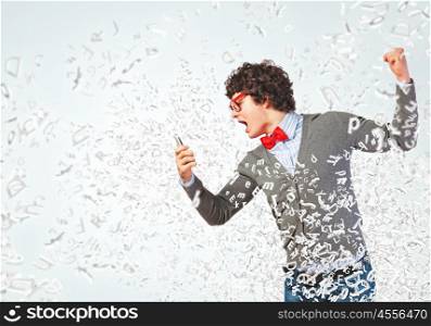 Young man shouting at his mobile phone. Young businessman with a red tie shouting furiously at his mobile phone