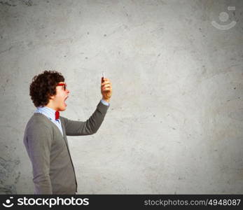 Young man shouting at his mobile phone. Young businessman with a red tie shouting furiously at his mobile phone