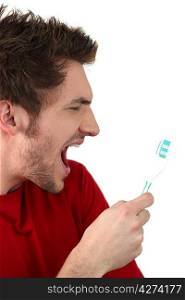 Young man shouting at his toothbrush