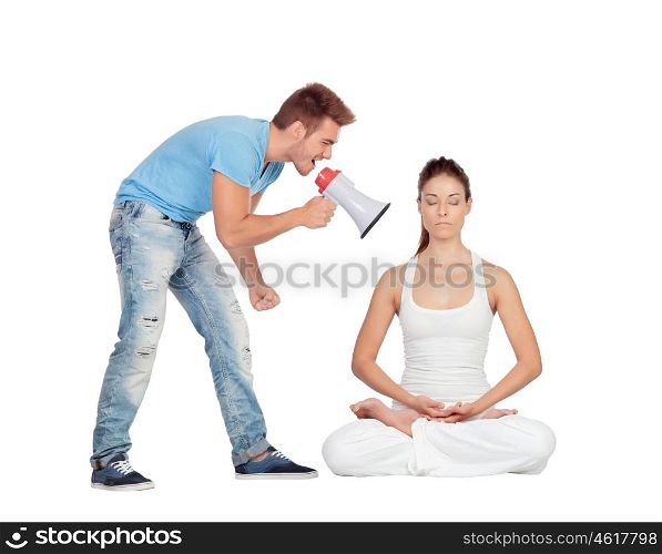 Young man shouting through a megaphone at a woman focused while doing yoga