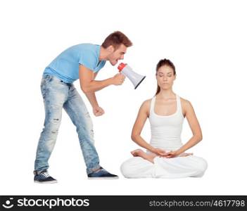 Young man shouting through a megaphone at a woman focused while doing yoga