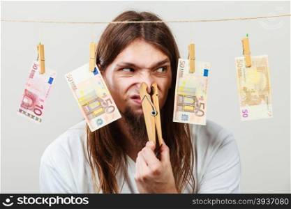 Young man sick of money. Money laundering concept. Young man with clothespin on his nose. Illegal business.