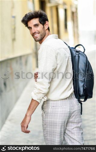 Young man sightseeing enjoying the streets of Granada, Spain. Male traveler carrying backpack in urban background.. Young man sightseeing enjoying the streets of Granada