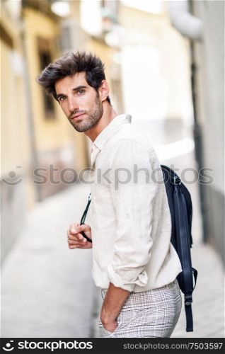 Young man sightseeing enjoying the streets of Granada, Spain. Male traveler carrying backpack in urban background.. Young man sightseeing enjoying the streets of Granada