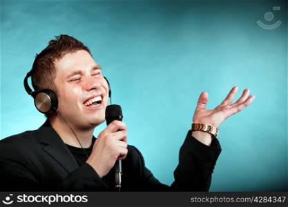 Young man singing into microphone. Happy karaoke signer studio shot blue background