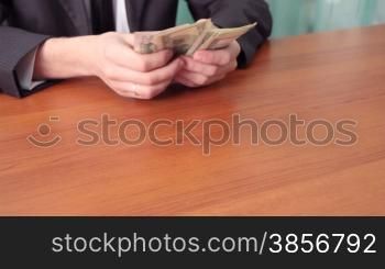 young man sits at a table at office and divides money.