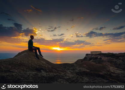Young man sitting and watching a beautiful sunset
