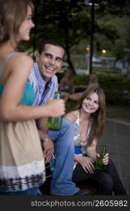 Young man sitting between two young women and smiling