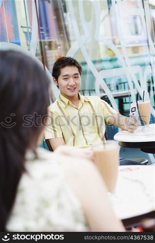 Young man sitting in a cafeteria and looking at mobile phone