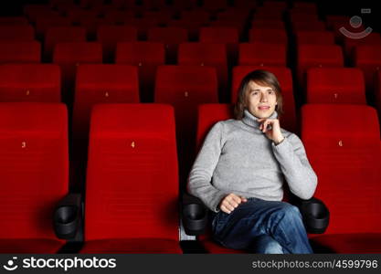 Young man sitting in cinema and watching movie