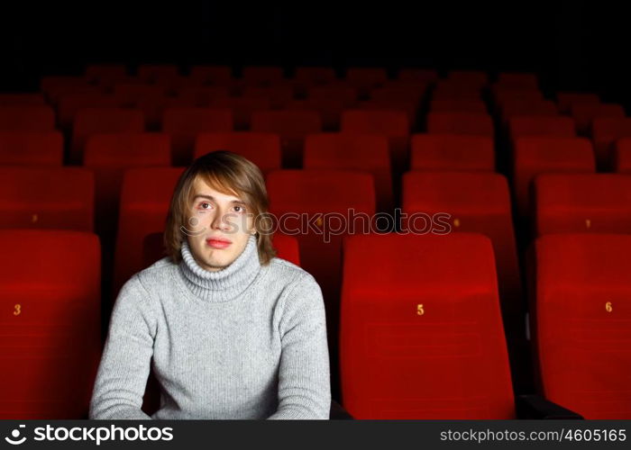 Young man sitting in cinema and watching movie