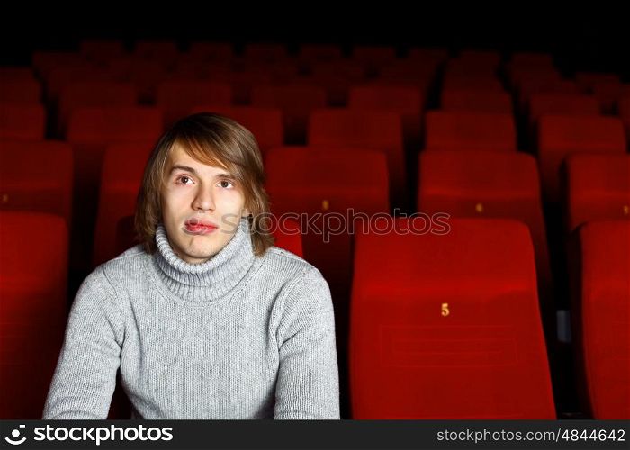 Young man sitting in cinema and watching movie