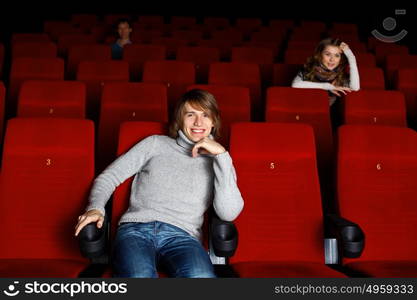 Young man sitting in cinema and watching movie