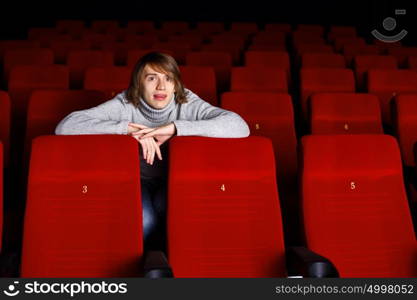 Young man sitting in cinema and watching movie