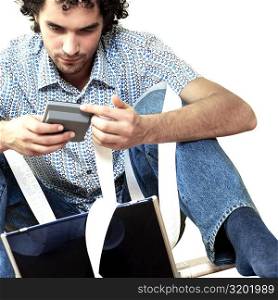 Young man sitting in front of a laptop holding a calculator