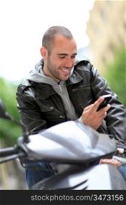 Young man sitting in motorcycle with telephone