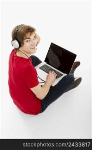 Young man sitting in the floor, and using computer with headphones
