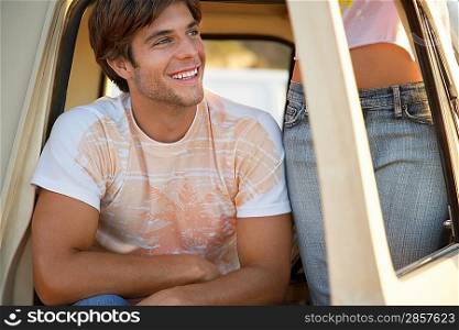 Young man sitting in van doorway young woman standing mid section