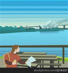 Young man sitting on a bench and holding a map, Sydney Opera House, Sydney, Australia