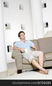 Young man sitting on a couch and holding a coffee cup