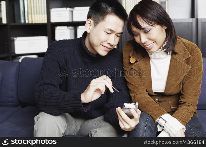 Young man sitting on a couch with a young woman holding a mobile phone