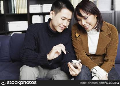 Young man sitting on a couch with a young woman holding a mobile phone