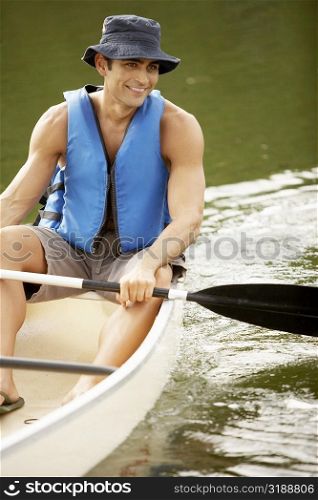 Young man sitting on a sailboat holding an oar