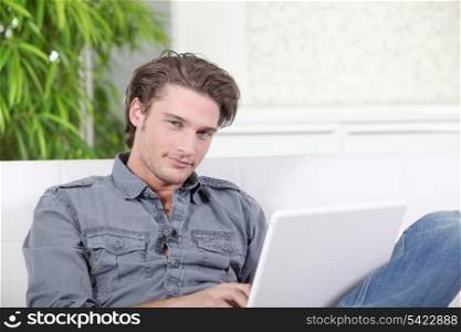 Young man sitting on a sofa with a laptop