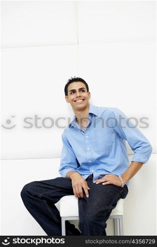 Young man sitting on a stool and smiling