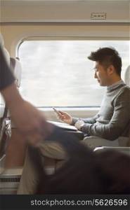 Young man sitting on a train using his phone
