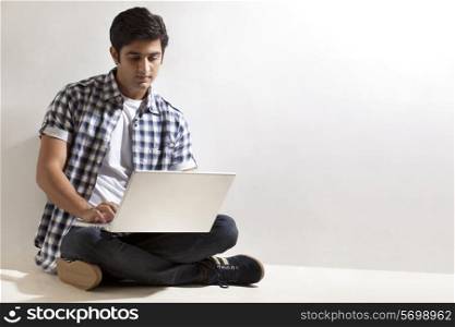Young man sitting on floor with laptop