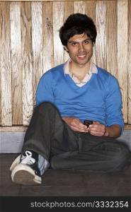 Young man sitting on floor with mobile phone