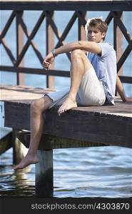 Young man sitting on jetty