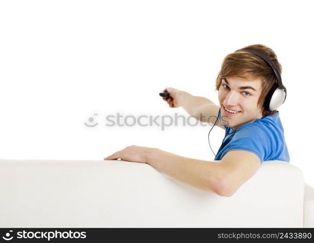 Young man sitting on the couch using a remote control, with copyspace for the designer