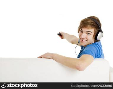 Young man sitting on the couch using a remote control, with copyspace for the designer