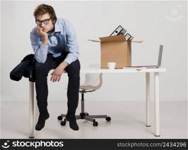 Young man sitting on the desk after being fired