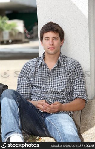 Young man sitting on the ground with mobile phone
