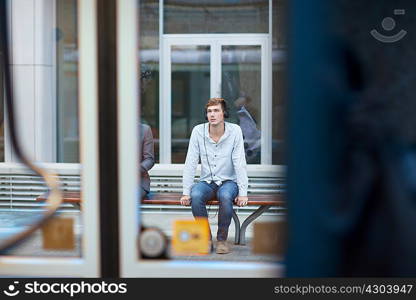 Young man sitting on train station bench