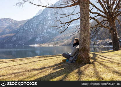 Young man sitting outdoors and enjoying mountains, snow, lake, good weather, blue sky, sun. Beautiful landscape. Time with yourself, dreaming, relaxation, mental health. Tourism, holiday and travel. Young man sitting outdoors and enjoying mountains, snow, lake, good weather, blue sky, sun. Beautiful landscape. Time with yourself, dreaming, relaxation, mental health. Tourism, holiday and travel.